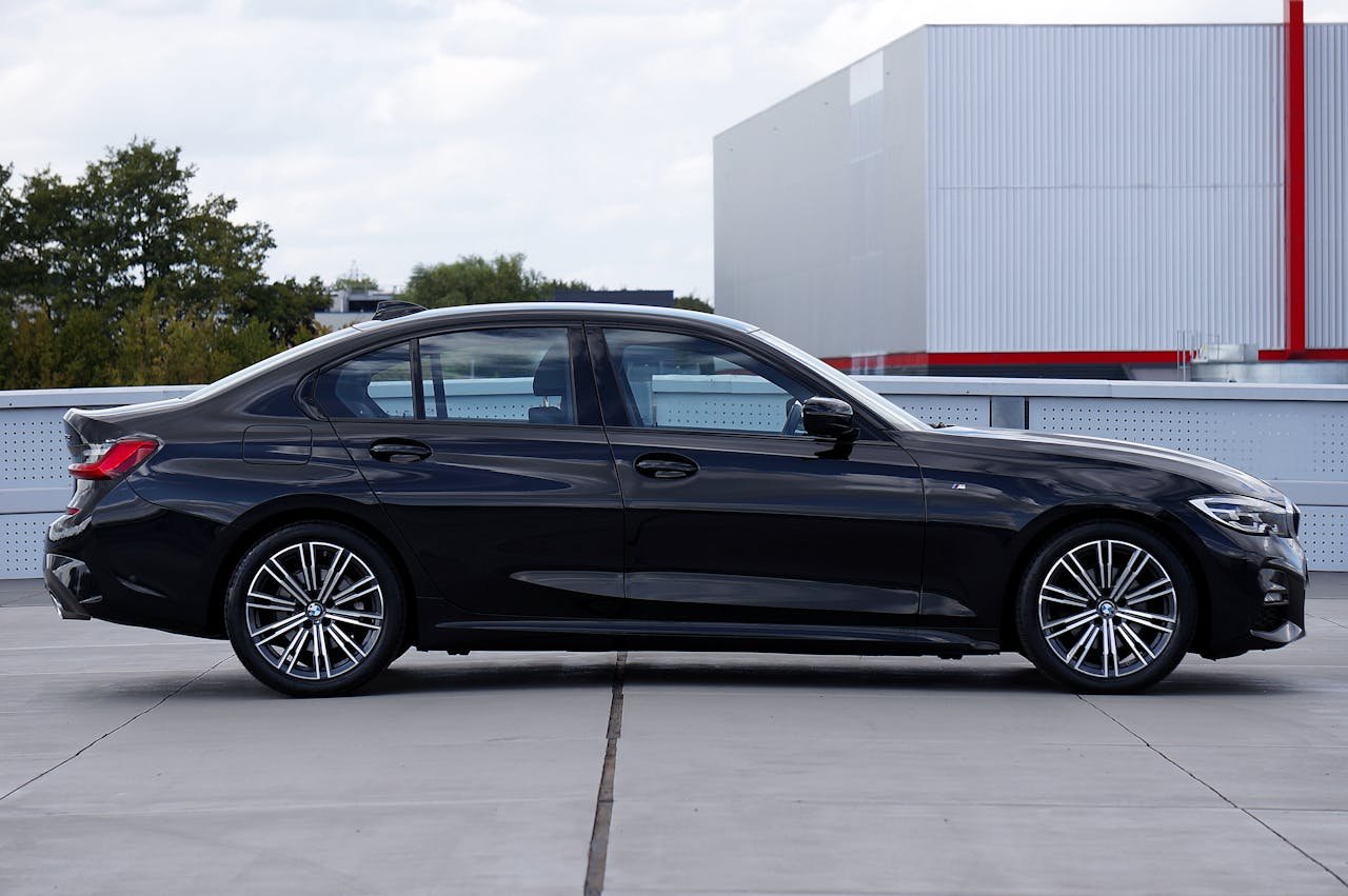 Services Side view of a black luxury sedan parked on pavement, showcasing modern design and elegance.